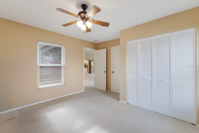 unfurnished bedroom featuring ceiling fan, a closet, and light carpet