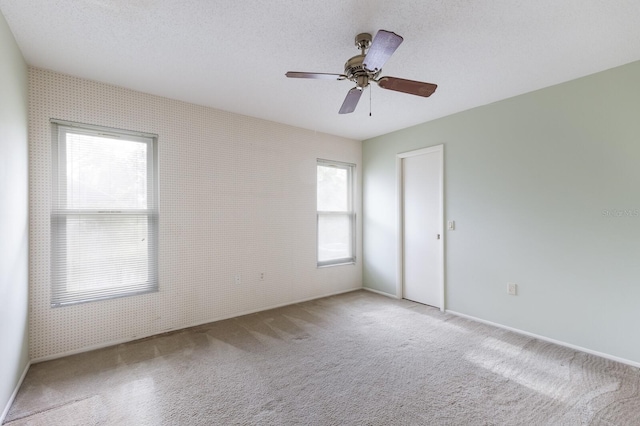 carpeted empty room with ceiling fan and a textured ceiling