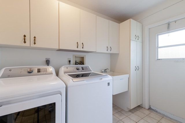 clothes washing area with cabinets, light tile patterned floors, sink, and washing machine and clothes dryer