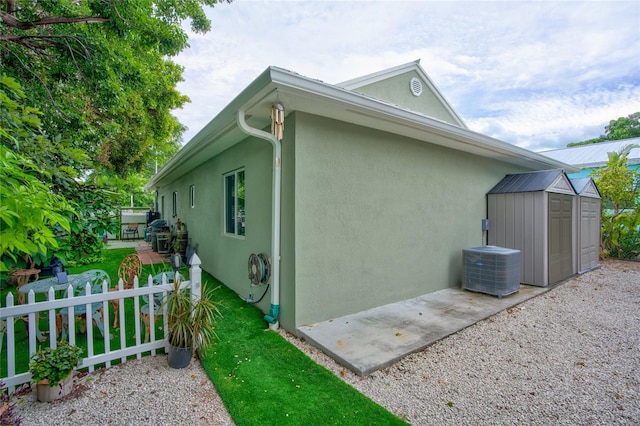 view of home's exterior with a shed and central AC