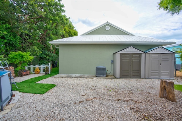 view of side of home featuring cooling unit and a shed