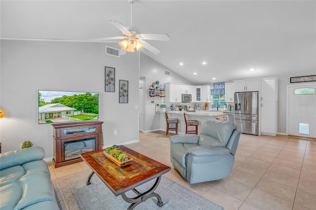 living room with lofted ceiling, light tile patterned floors, a fireplace, and ceiling fan