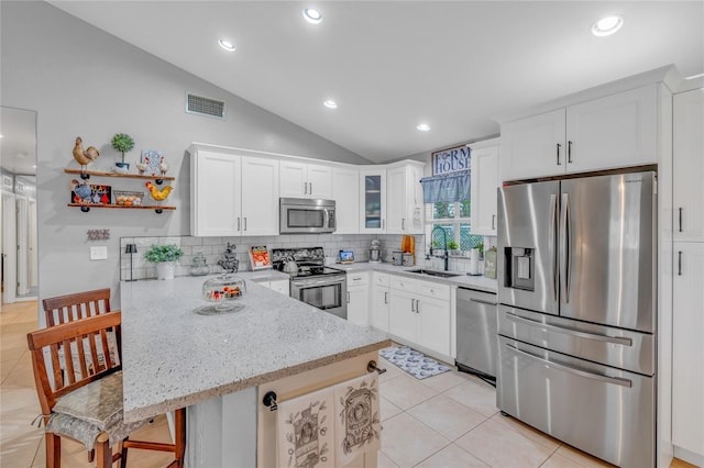 kitchen featuring appliances with stainless steel finishes, a kitchen breakfast bar, sink, and white cabinets