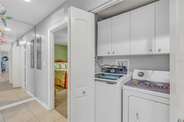 laundry room with cabinets, light tile patterned floors, and washer and clothes dryer