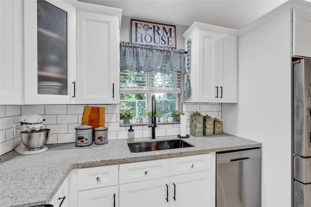 kitchen featuring appliances with stainless steel finishes, tasteful backsplash, sink, white cabinets, and light stone counters