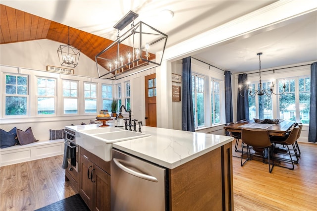 kitchen with a kitchen island with sink, hanging light fixtures, stainless steel dishwasher, a notable chandelier, and light hardwood / wood-style floors