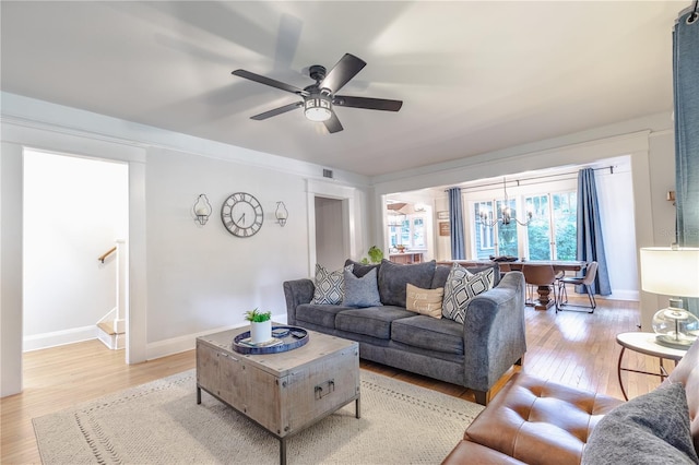 living room with ceiling fan with notable chandelier and light hardwood / wood-style floors