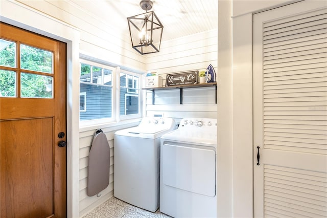 laundry room featuring washer and dryer, a chandelier, and wood walls