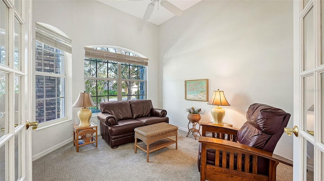 living room with light carpet, french doors, a towering ceiling, and ceiling fan