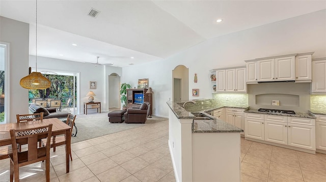 kitchen with kitchen peninsula, vaulted ceiling, ceiling fan, sink, and decorative light fixtures