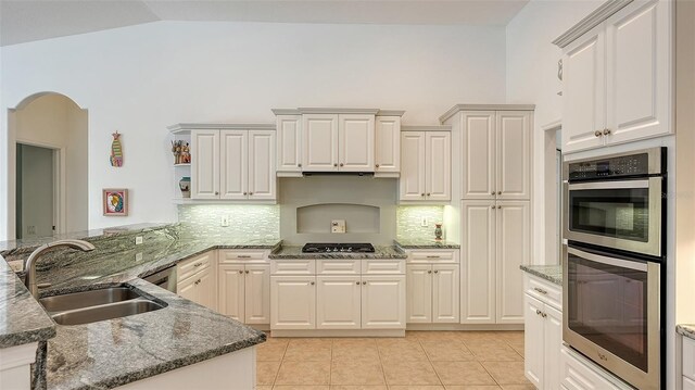 9506 Royal Calcutta Pl, Lakewood Ranch, FL 34202 - kitchen with stainless steel double oven, a sink, decorative backsplash, light tile patterned floors, and high vaulted ceiling