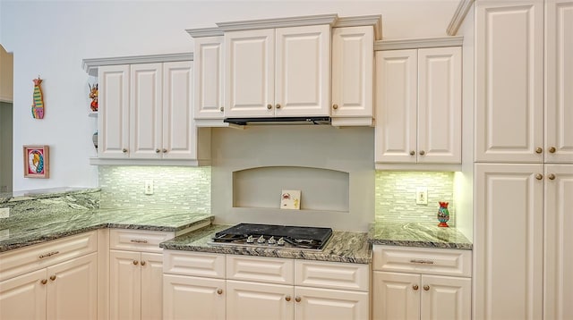 kitchen featuring tasteful backsplash, dark stone countertops, white cabinetry, and stainless steel gas cooktop