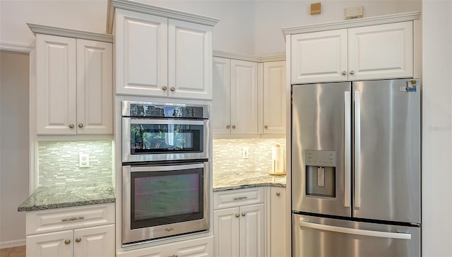 kitchen with decorative backsplash, white cabinets, light stone counters, and appliances with stainless steel finishes