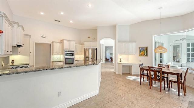 kitchen with ceiling fan, stainless steel appliances, dark stone counters, pendant lighting, and vaulted ceiling