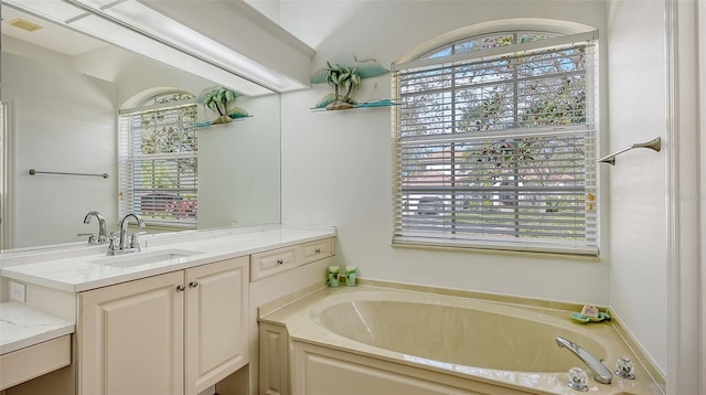 bathroom featuring a tub to relax in, a wealth of natural light, and vanity