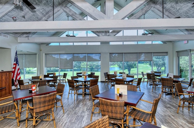 dining area with a wealth of natural light, beamed ceiling, high vaulted ceiling, and hardwood / wood-style flooring