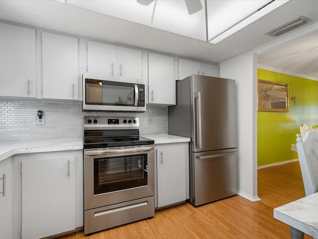 kitchen featuring white cabinets, appliances with stainless steel finishes, tasteful backsplash, and light hardwood / wood-style flooring