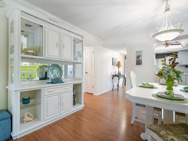 interior space with a textured ceiling, light hardwood / wood-style flooring, ceiling fan, and ornamental molding