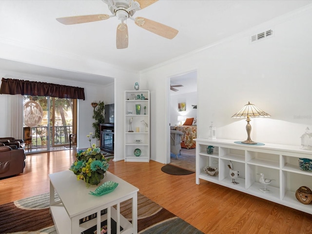 living room with hardwood / wood-style floors, ceiling fan, and ornamental molding