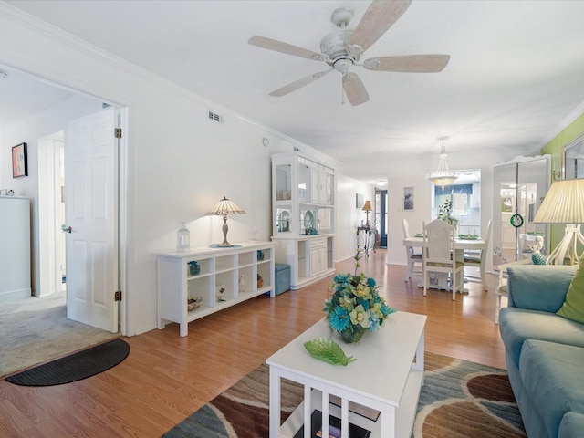 living room with light hardwood / wood-style floors, ceiling fan, and crown molding