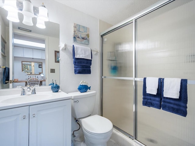 bathroom featuring a shower with door, vanity, a textured ceiling, and toilet