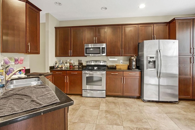 kitchen with sink, appliances with stainless steel finishes, and dark stone counters