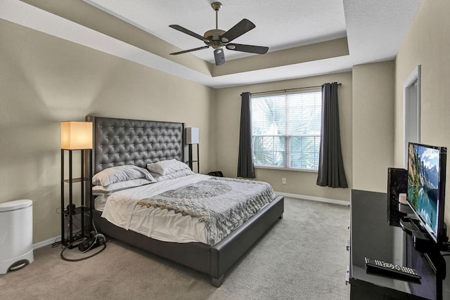 bedroom with carpet flooring, ceiling fan, and a tray ceiling