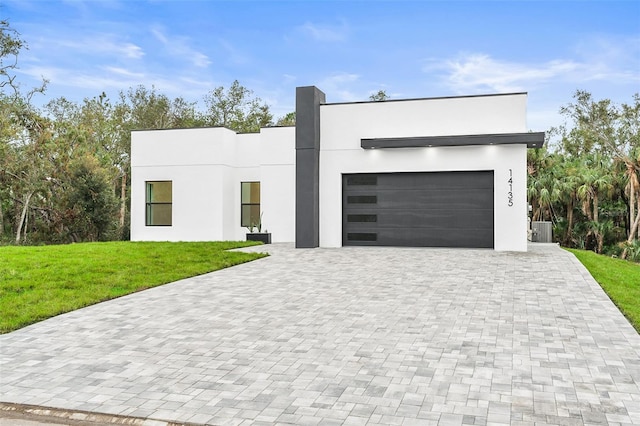 contemporary home with central air condition unit, a front lawn, and a garage