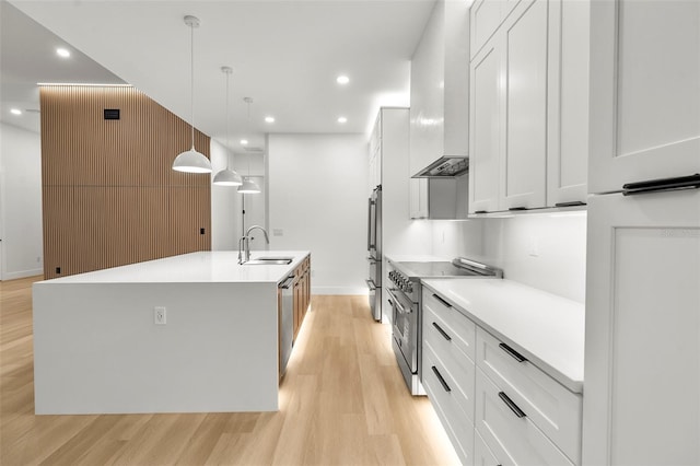 kitchen featuring white cabinets, decorative light fixtures, stainless steel appliances, and a large island with sink