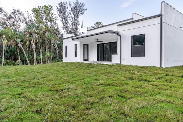 back of property featuring ceiling fan and a lawn