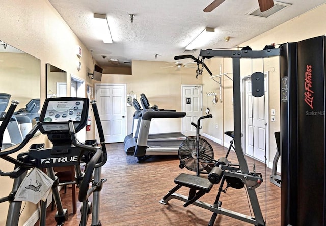 workout area with ceiling fan, wood-type flooring, and a textured ceiling