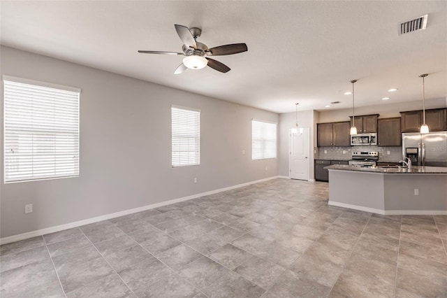 kitchen featuring dark brown cabinetry, ceiling fan, hanging light fixtures, tasteful backsplash, and appliances with stainless steel finishes