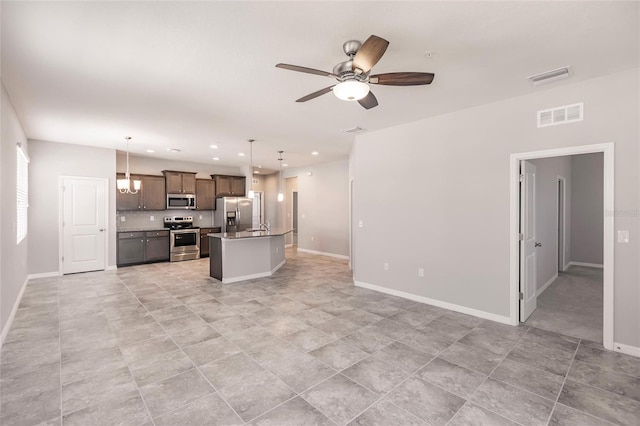 kitchen featuring appliances with stainless steel finishes, a center island with sink, ceiling fan, and pendant lighting