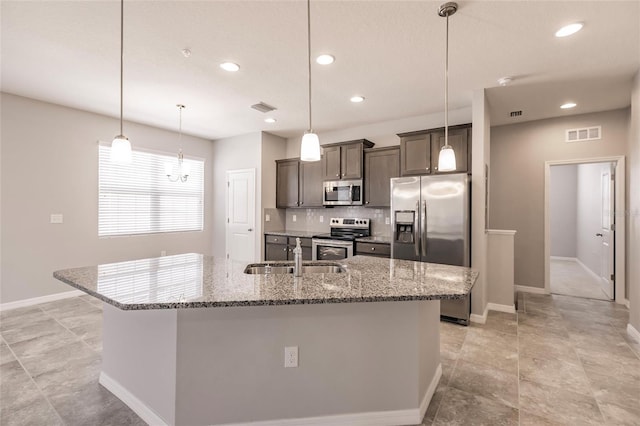 kitchen featuring stone counters, sink, stainless steel appliances, and a kitchen island with sink