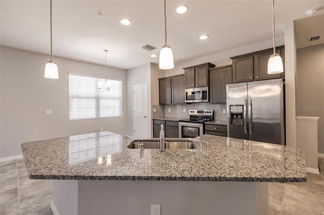 kitchen with appliances with stainless steel finishes, dark brown cabinetry, and decorative light fixtures