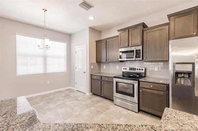 kitchen featuring light stone countertops, dark brown cabinets, decorative light fixtures, and appliances with stainless steel finishes