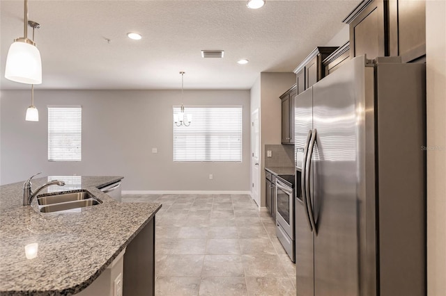 kitchen featuring sink, hanging light fixtures, light stone counters, dark brown cabinets, and appliances with stainless steel finishes