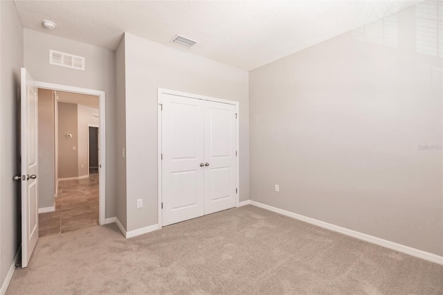 unfurnished bedroom with light colored carpet and a closet