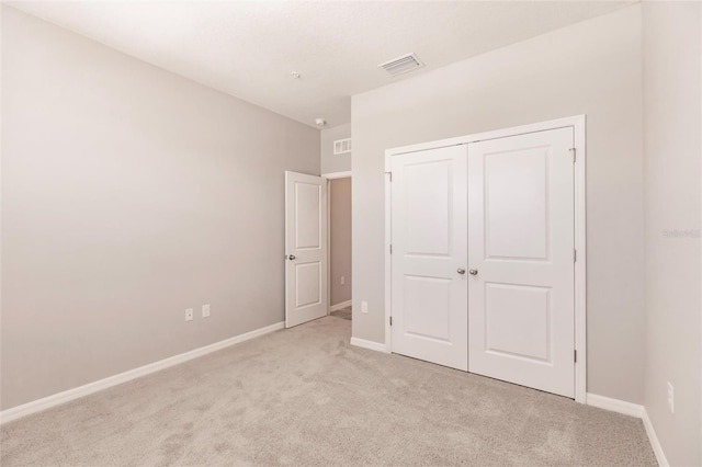 unfurnished bedroom with a closet and light colored carpet