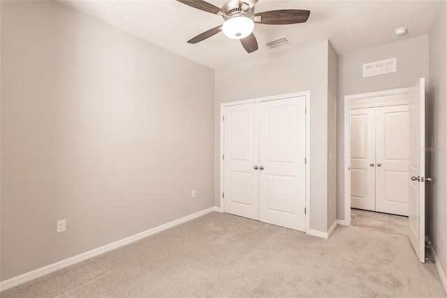 unfurnished bedroom featuring a closet, light colored carpet, and ceiling fan