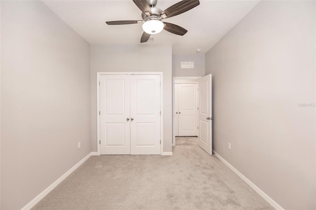 unfurnished bedroom with ceiling fan, light carpet, and a closet