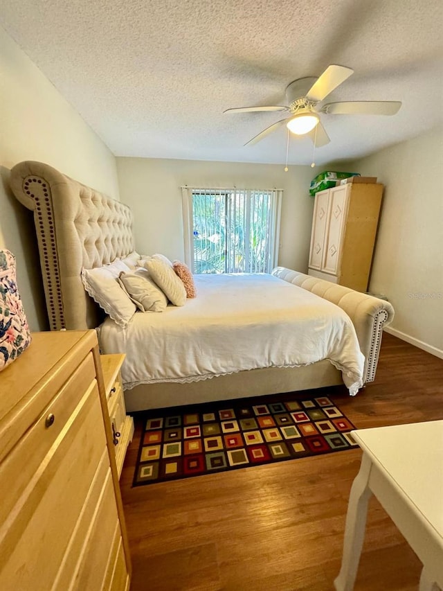 bedroom with hardwood / wood-style floors, ceiling fan, and a textured ceiling