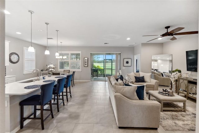 tiled living room featuring sink and ceiling fan with notable chandelier