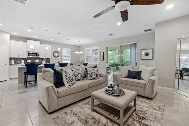 living room with light tile patterned floors and ceiling fan with notable chandelier