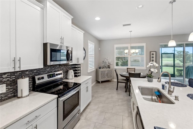 kitchen with hanging light fixtures, sink, decorative backsplash, appliances with stainless steel finishes, and white cabinetry