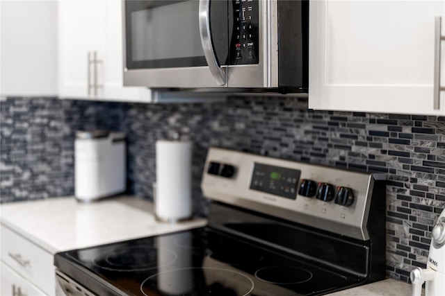 kitchen featuring white cabinets, decorative backsplash, and stainless steel appliances