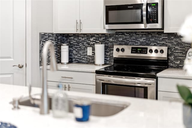 kitchen with decorative backsplash, appliances with stainless steel finishes, white cabinetry, and sink