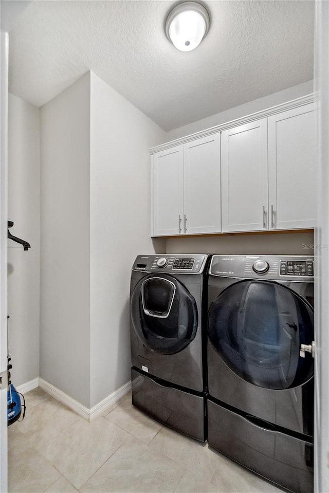 laundry room featuring light tile patterned floors, cabinets, a textured ceiling, and independent washer and dryer