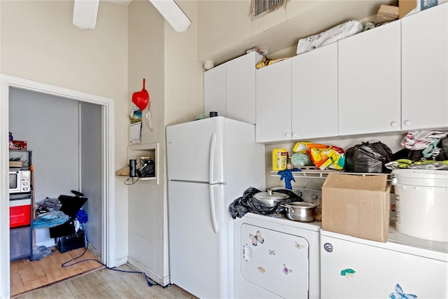 kitchen with washer / dryer, white refrigerator, light hardwood / wood-style floors, and white cabinetry