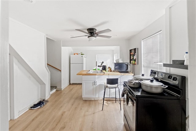 kitchen featuring black appliances, white cabinets, ceiling fan, light wood-type flooring, and a breakfast bar area